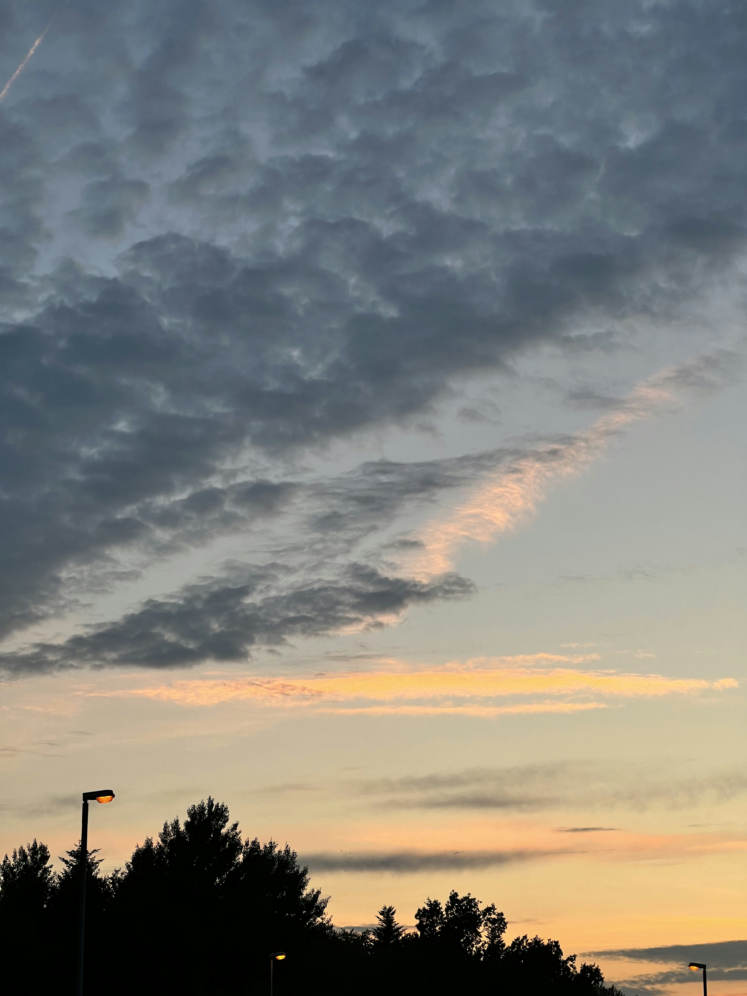 a plane flying through a cloudy sky at sunset