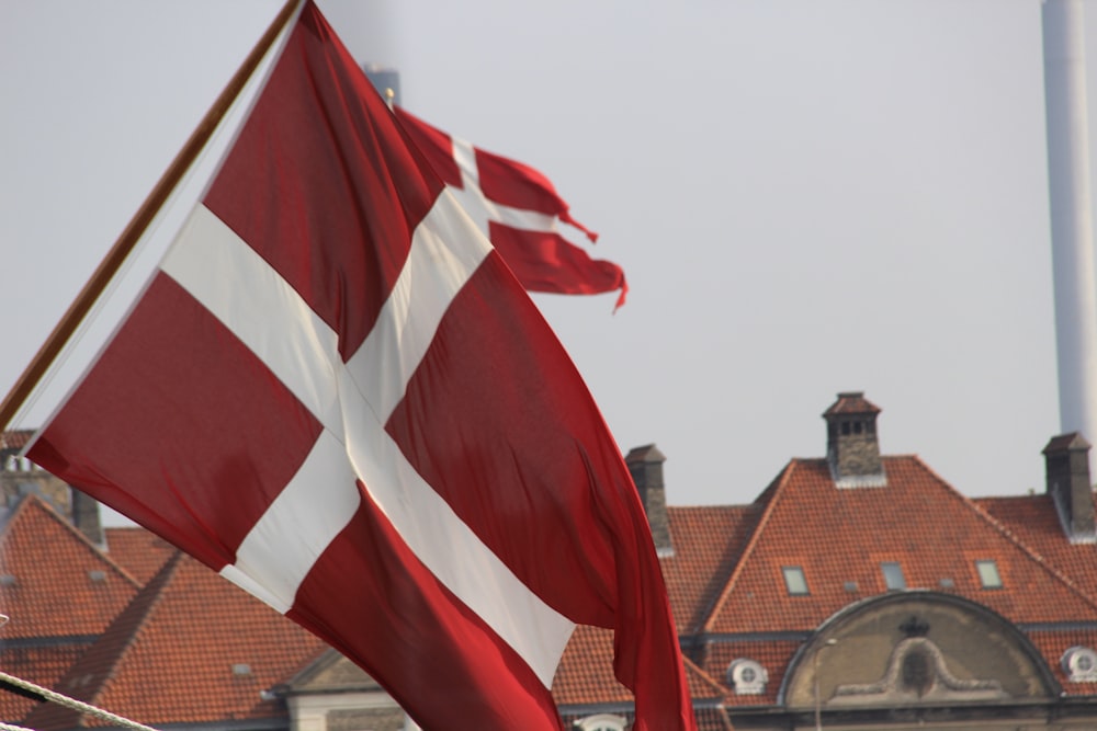a red and white flag flying in front of a building