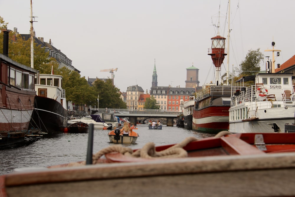 a river filled with lots of boats next to tall buildings