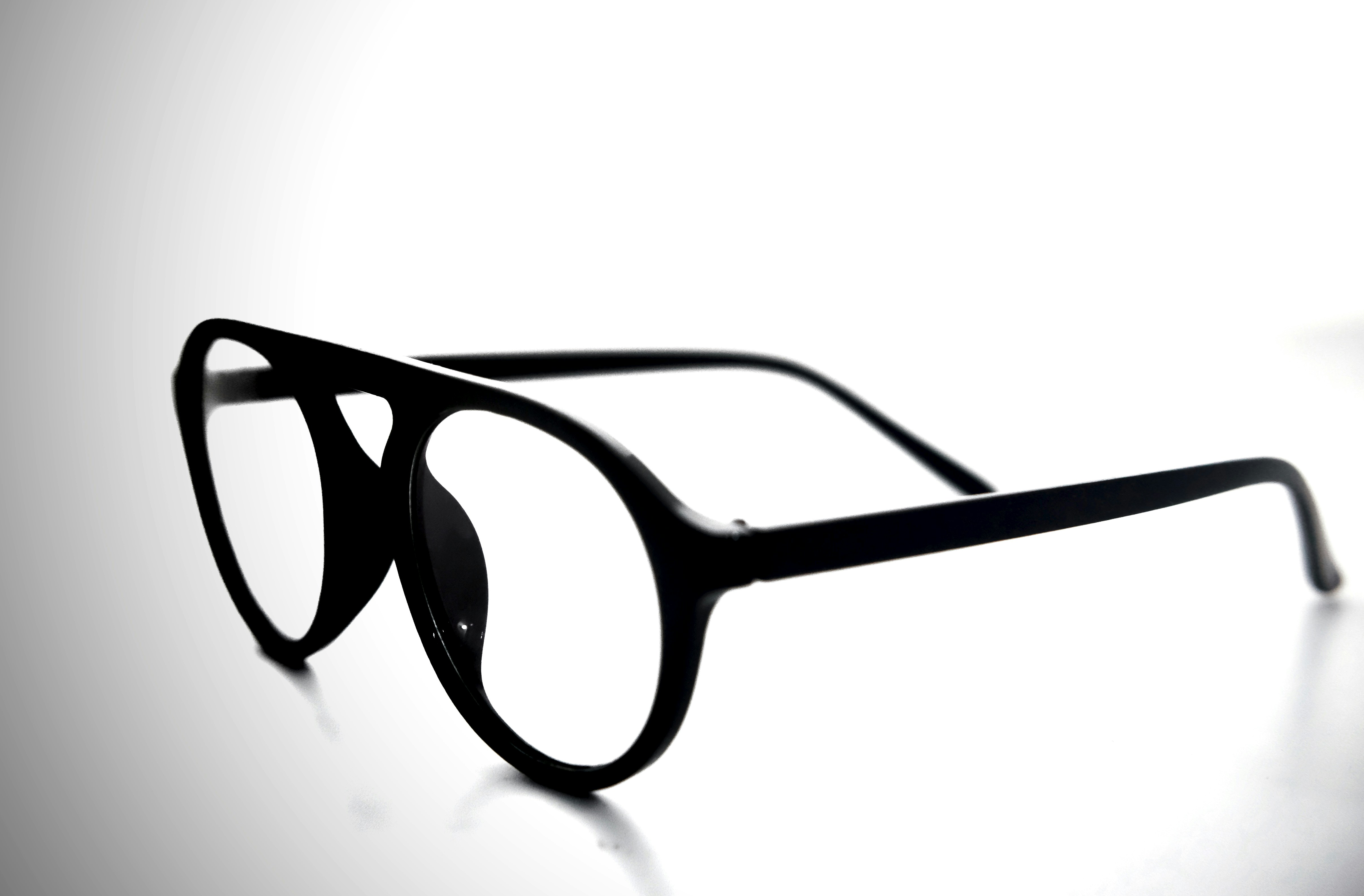 Titanium aviator sunglasses on reflective black surface, dark moody studio lighting