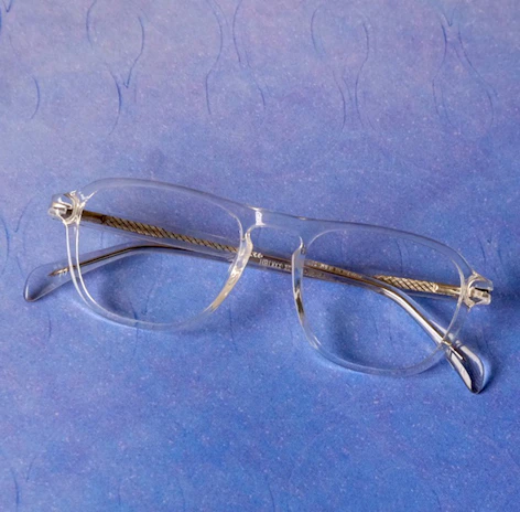 A patient trying on ultra-modern glasses with bright blue eyes visible through the lenses.