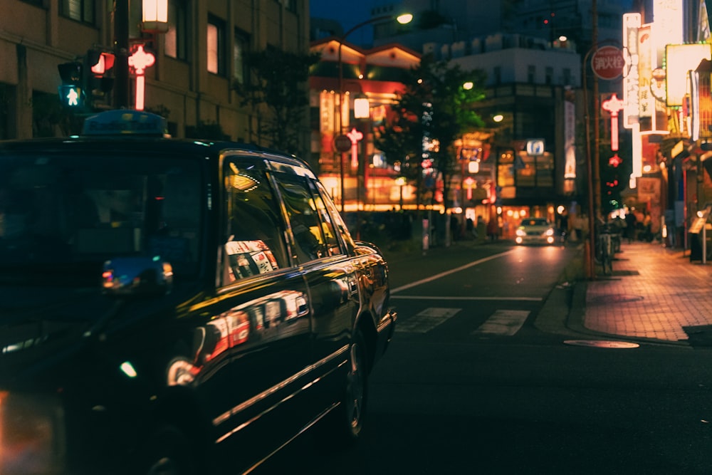 a taxi cab driving down a city street at night