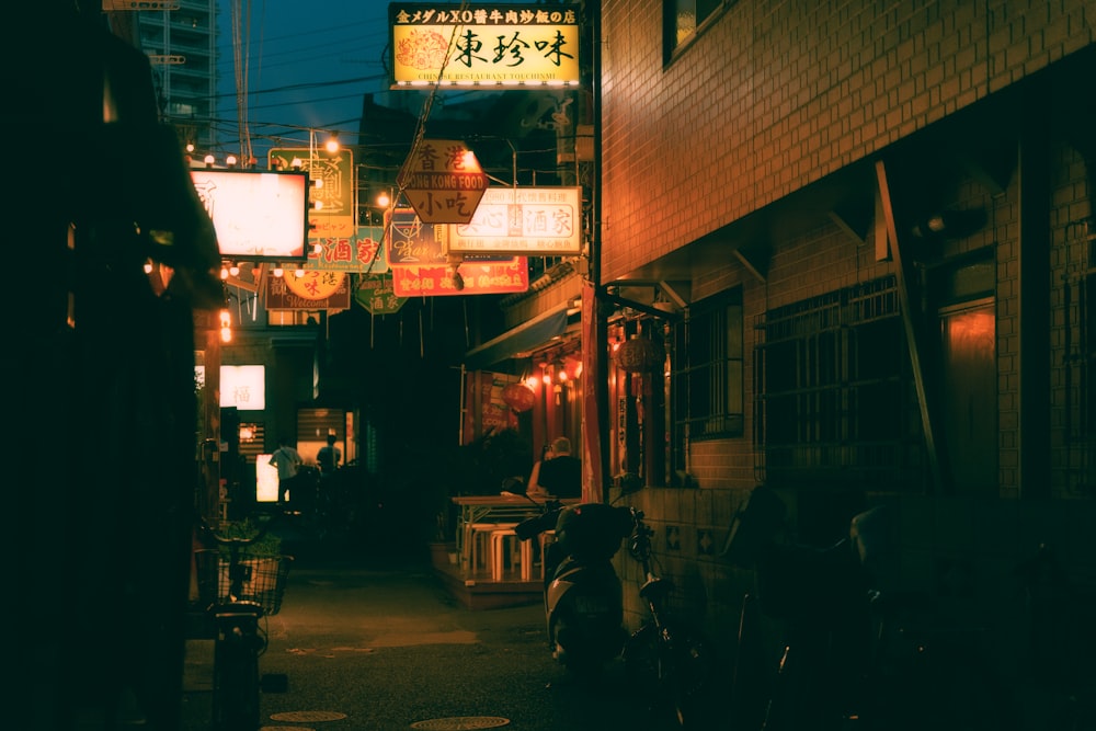 a narrow alley way with a neon sign above it