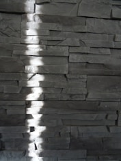 a shadow of a person standing in front of a stone wall