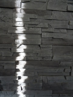 a shadow of a person standing in front of a stone wall