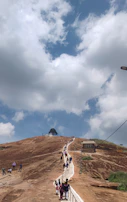 Group of trainees climbing a tall ladder against a cloudy sky.