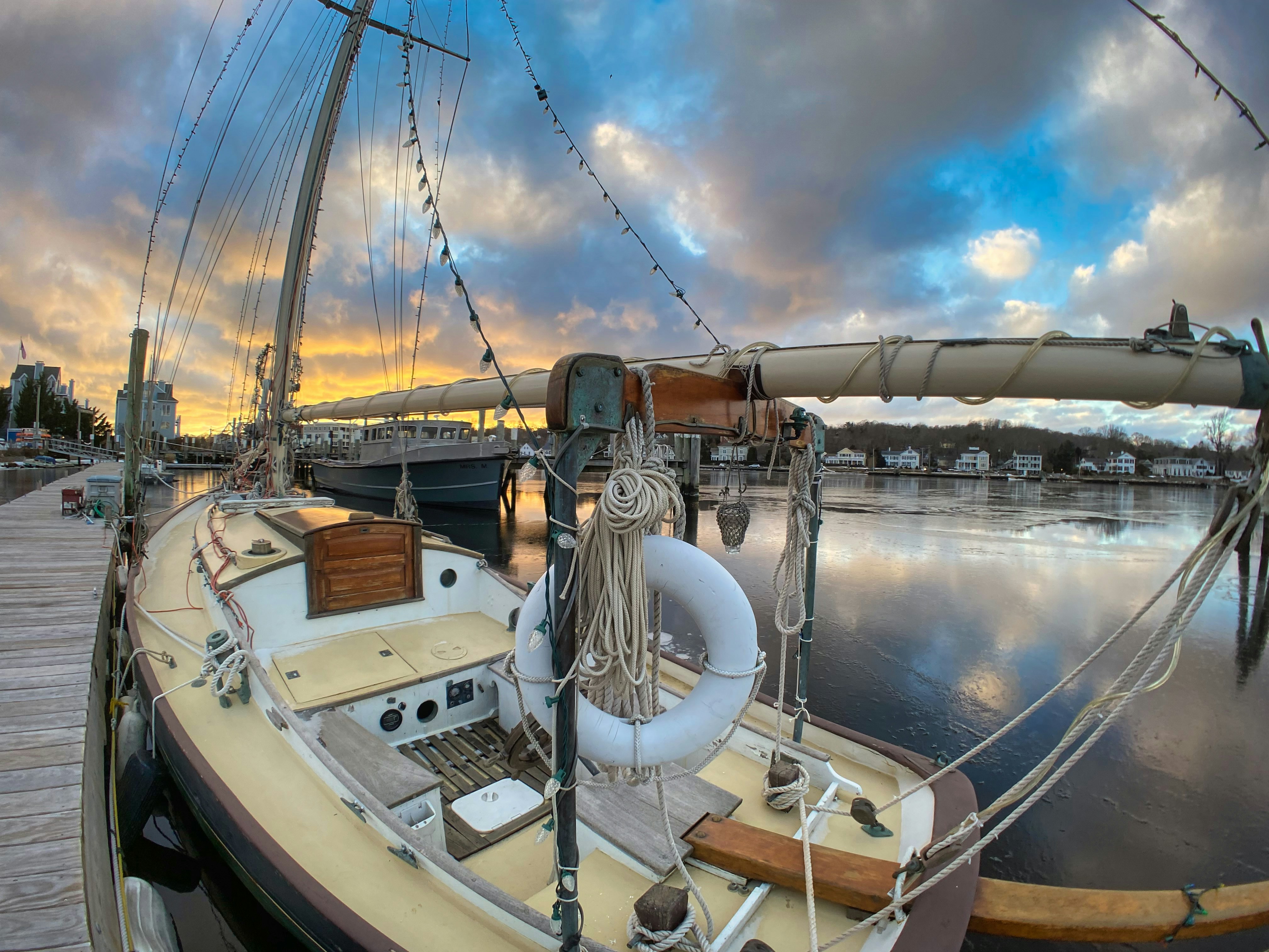 a sailboat docked at a dock with a cloudy sky in the background