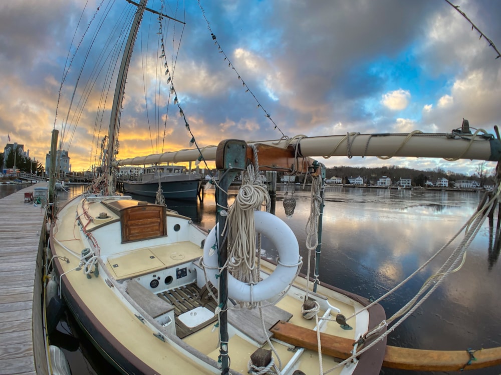 a sailboat docked at a dock with a cloudy sky in the background