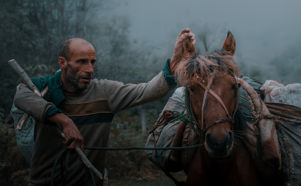 a man standing next to a brown horse