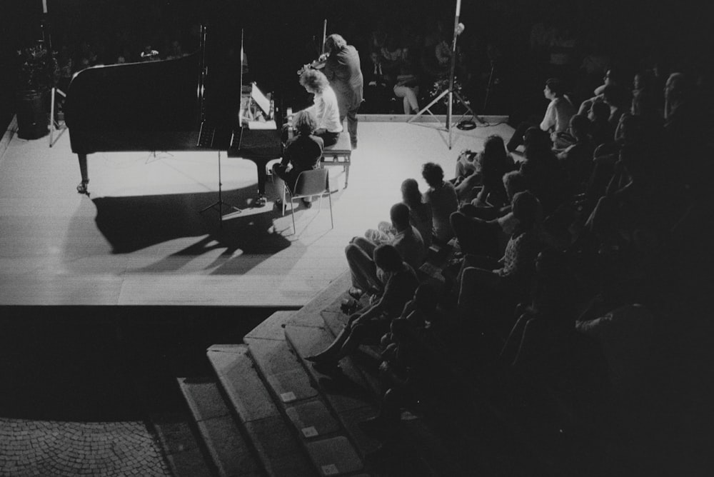 a black and white photo of a man playing a piano