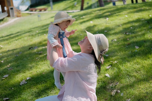 A joyful mother playing with her children in a sunlit park.