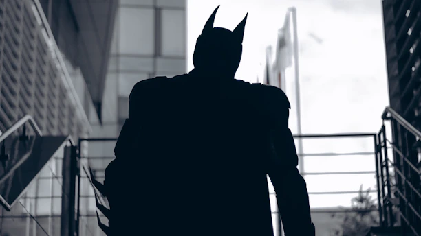 Dark silhouette of a focused man standing alone in a shadowy urban environment.