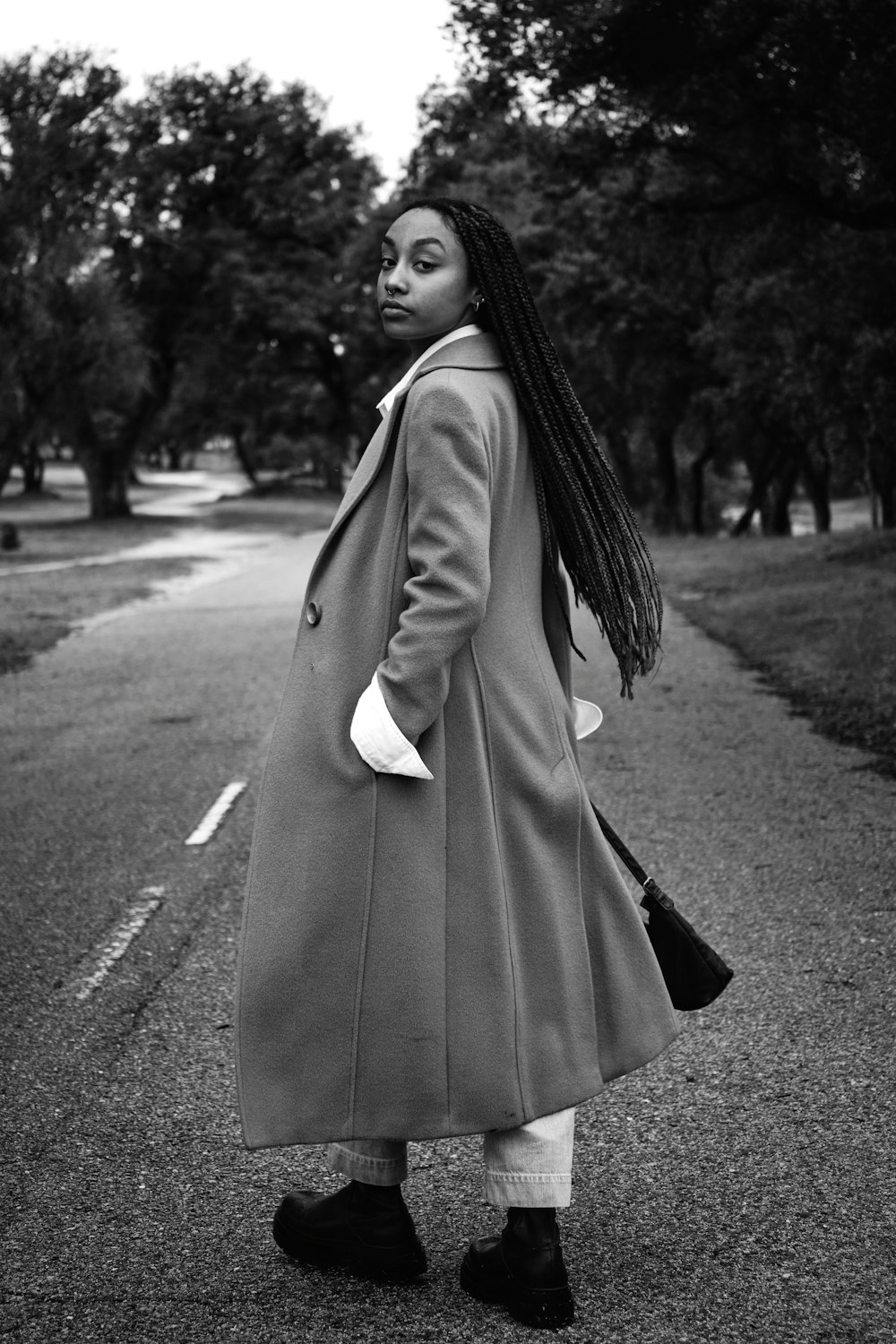 a black and white photo of a woman in a coat