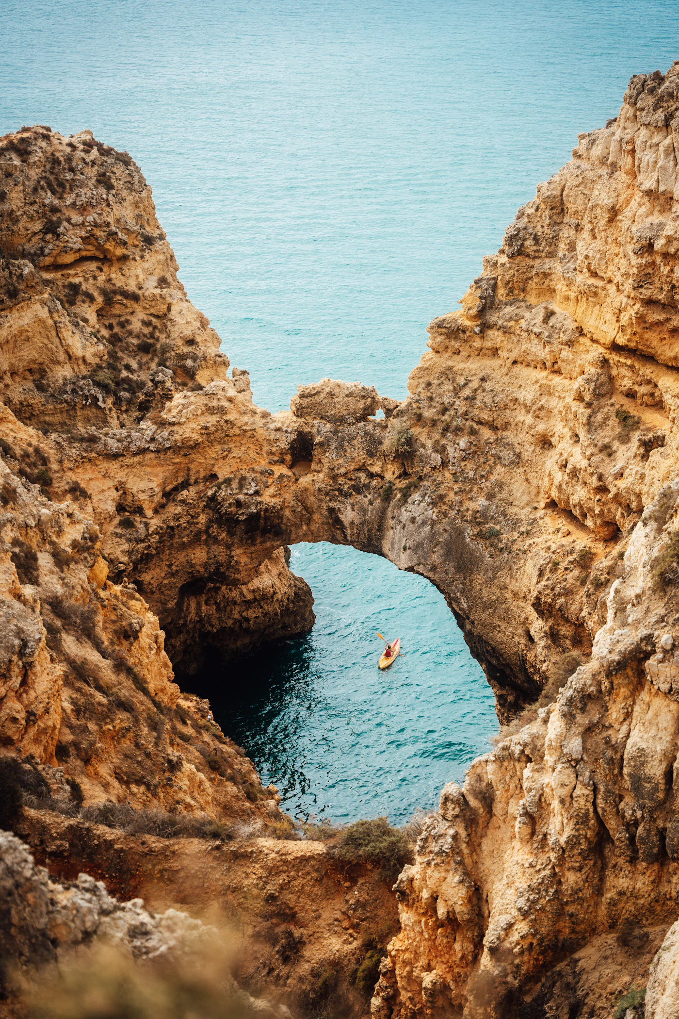 Kayaker moving through clear coastal water between rock formations