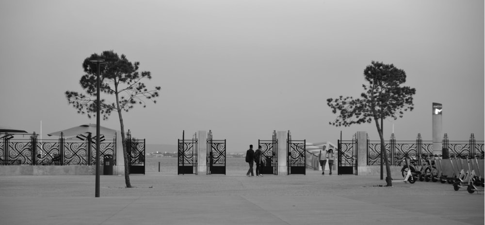 a black and white photo of a couple standing in front of a gate