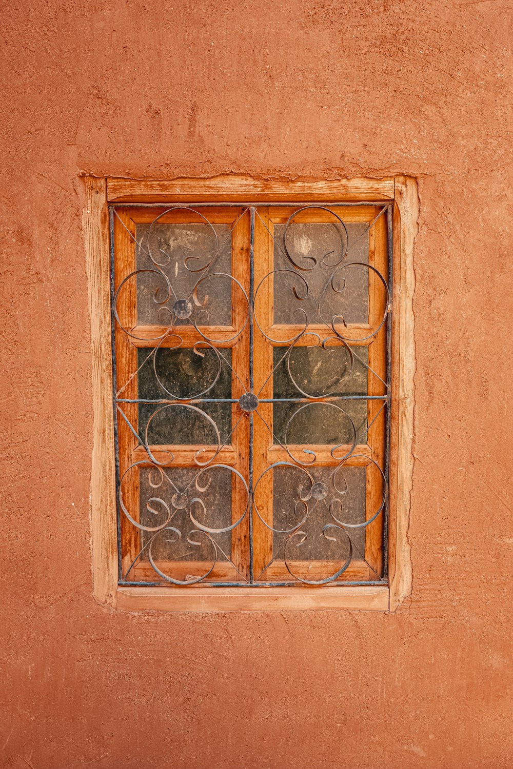 a window with iron bars on a stucco wall