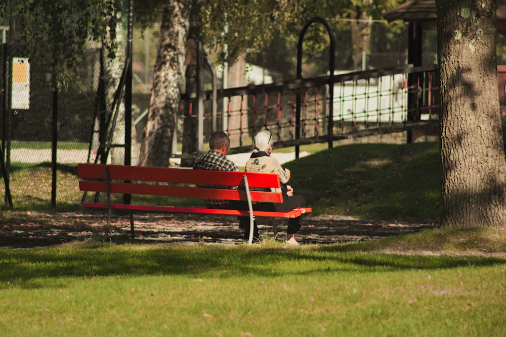 a man sitting on a red bench in a park