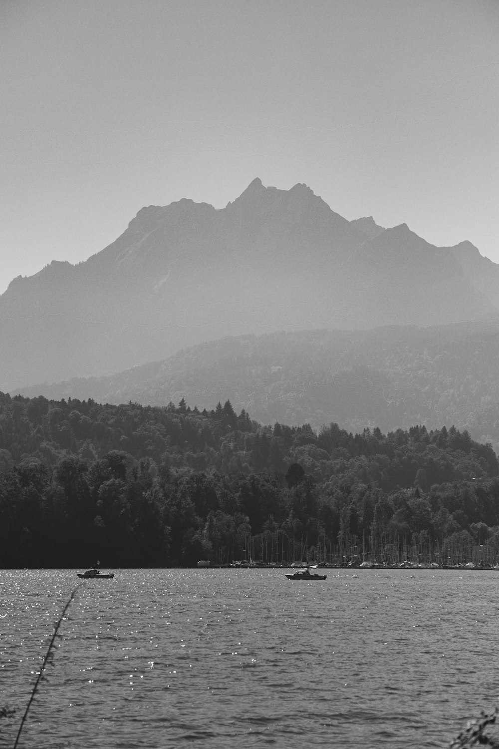 uma foto em preto e branco de um lago com montanhas ao fundo