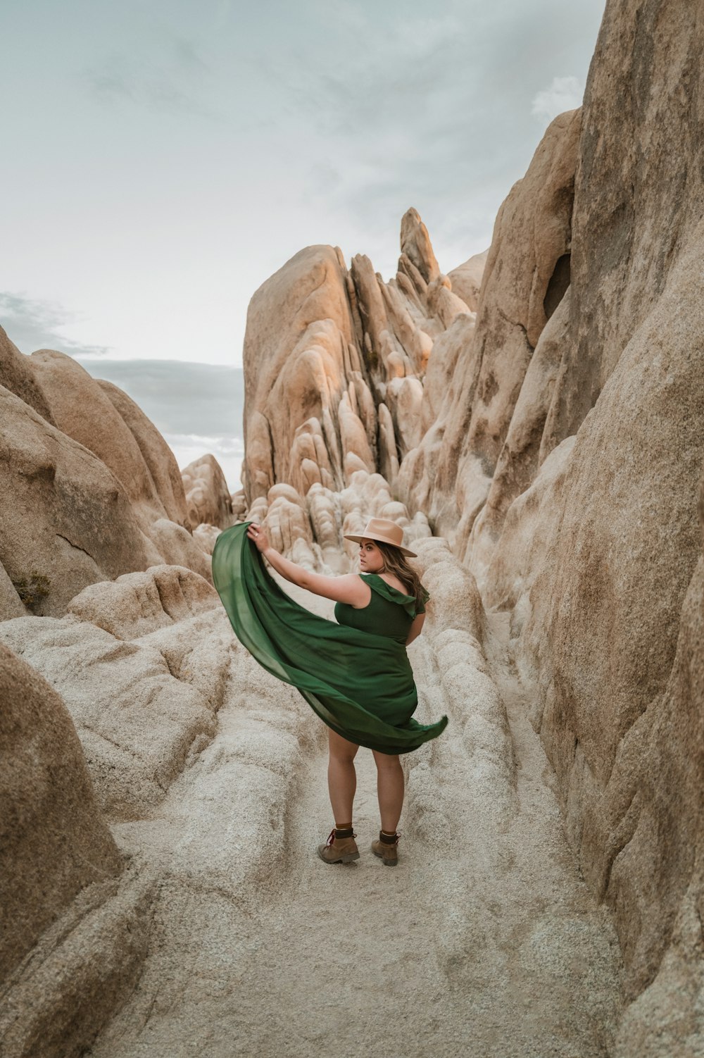 a woman in a green dress standing in a rocky area