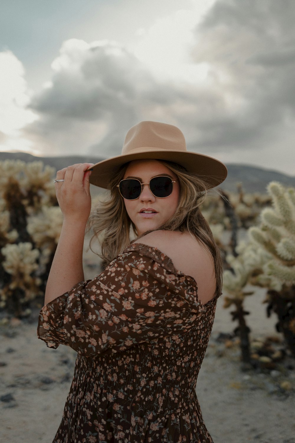 a woman wearing a hat and sunglasses in a desert