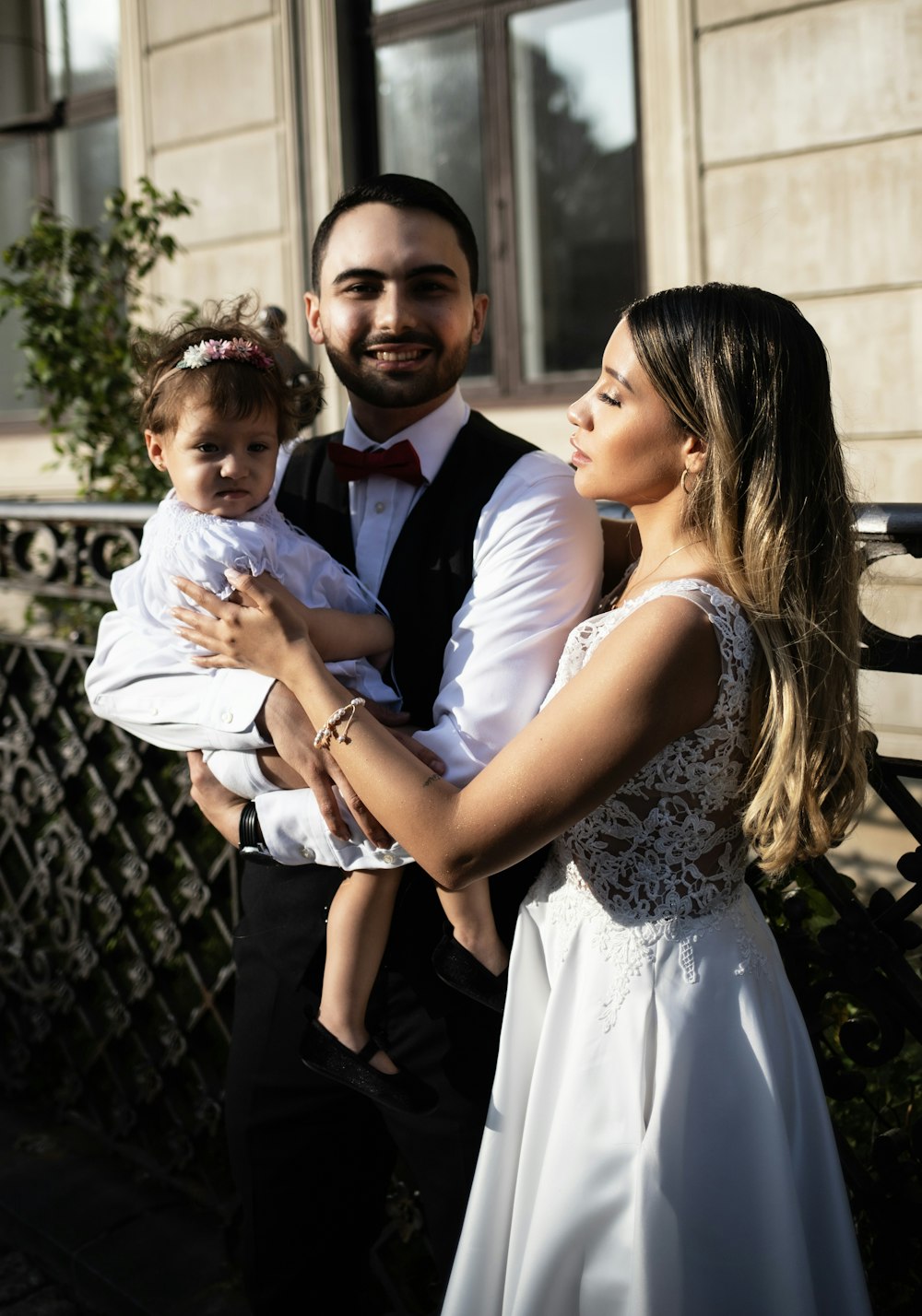 a man in a tuxedo holding a baby and a woman in a dress