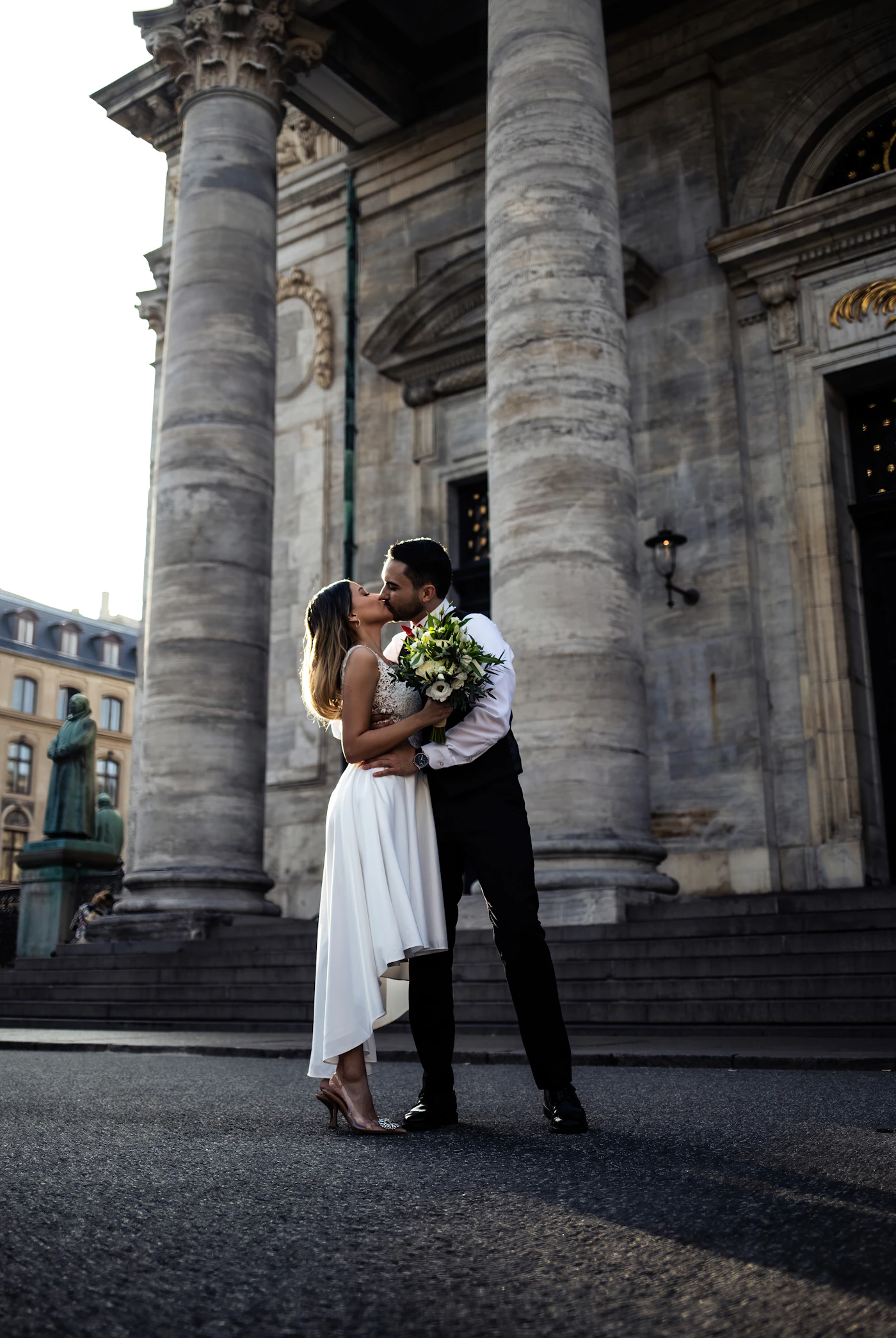 Couple in elopement attire at the fortification gate entrance of Old Quebec City with the stone walls and the towers of the historic city visible behind them