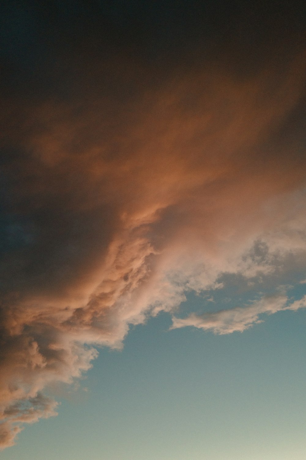 a plane flying through a cloudy sky at sunset