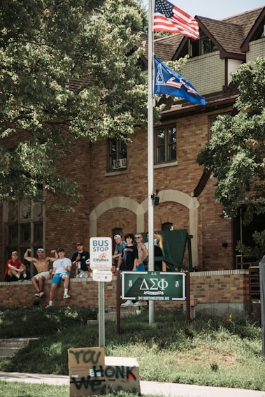 A proud group photo of Omega Pi Alpha fraternity members gathered outside a historic university building during chapter induction day.