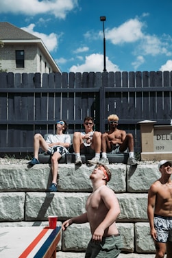 A group of young men sharing a supportive moment outdoors with warm sunlight.
