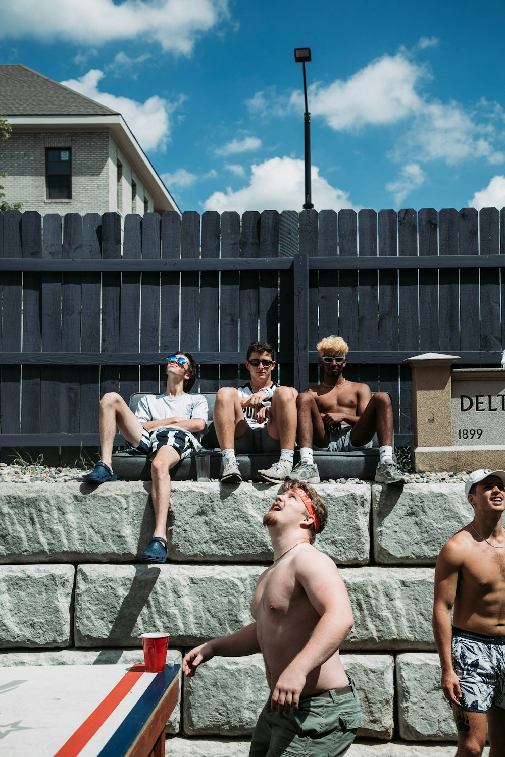 a group of young men sitting on top of a stone wall