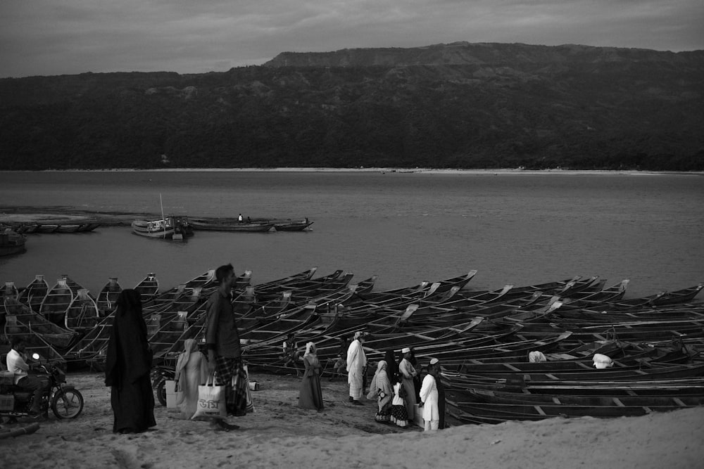 a group of people standing next to boats on a beach