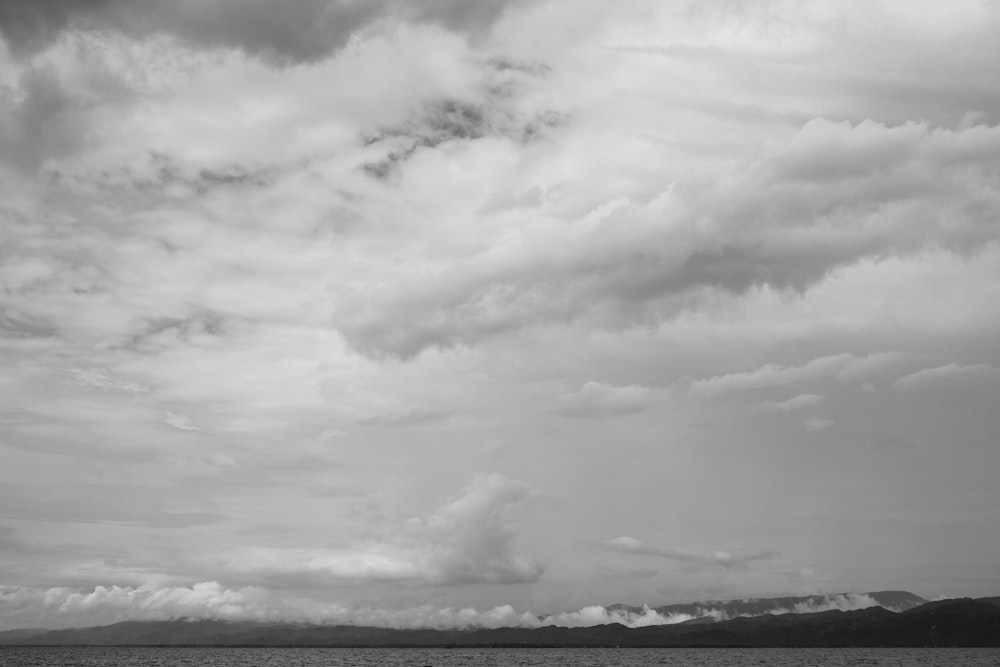 a black and white photo of clouds over a body of water