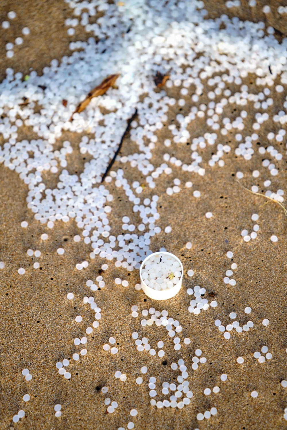 un reloj blanco sentado en la parte superior de una playa de arena