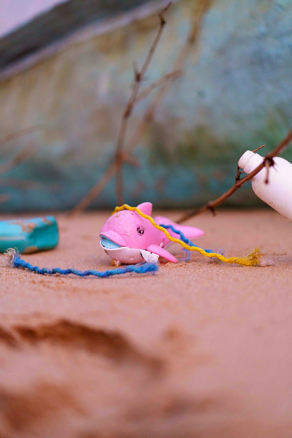 Ein rosafarbener Spielzeugfisch liegt auf dem Sand