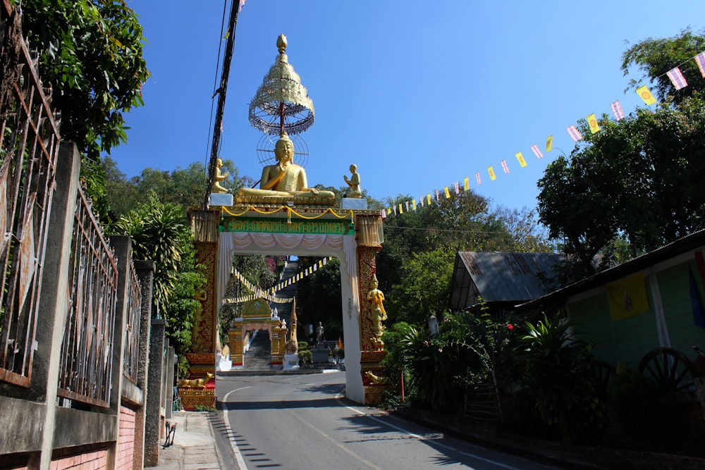 Una grande statua dorata di Buddha seduta in cima a un cancello di legno