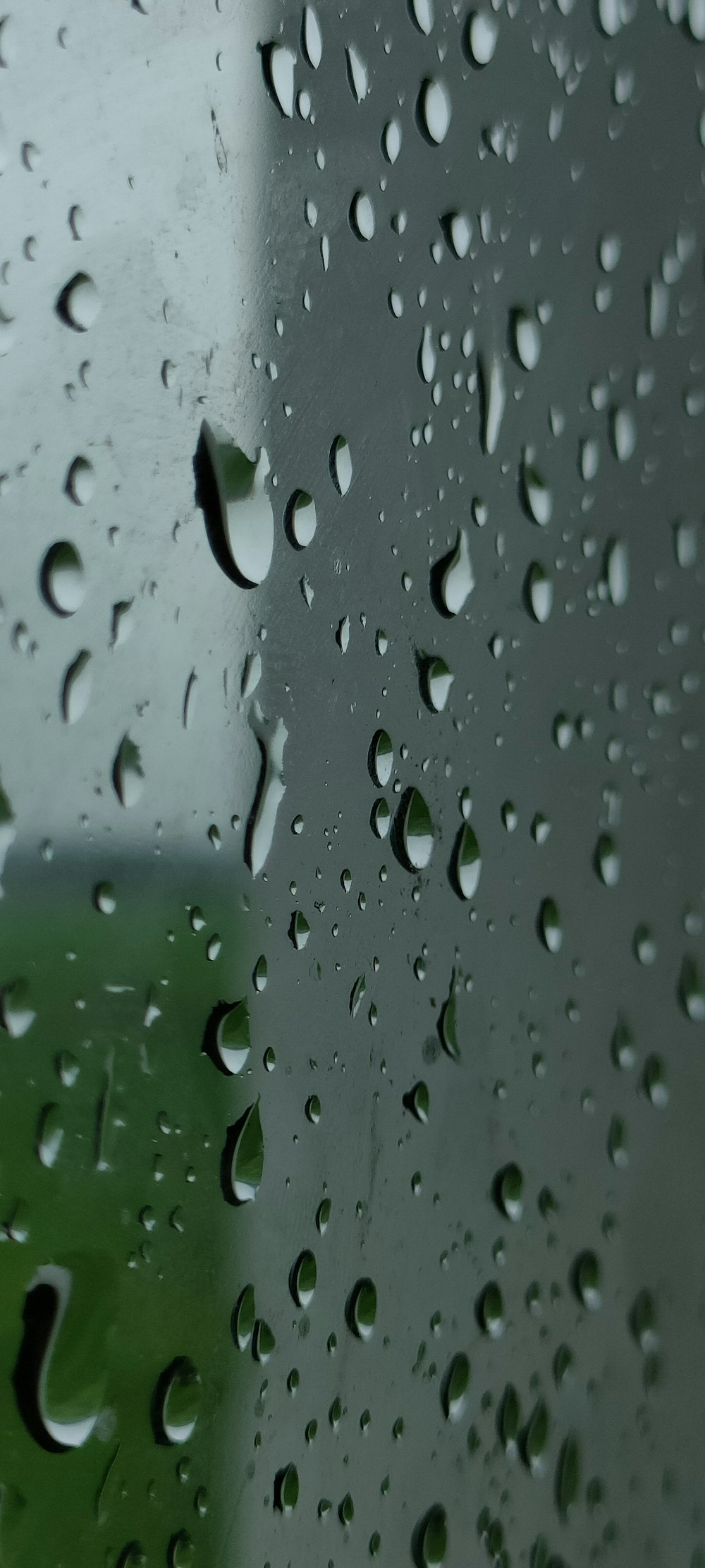 rain drops on a window with a green field in the background