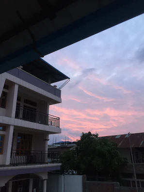 Finished residential building with balconies and landscaped surroundings at sunset.