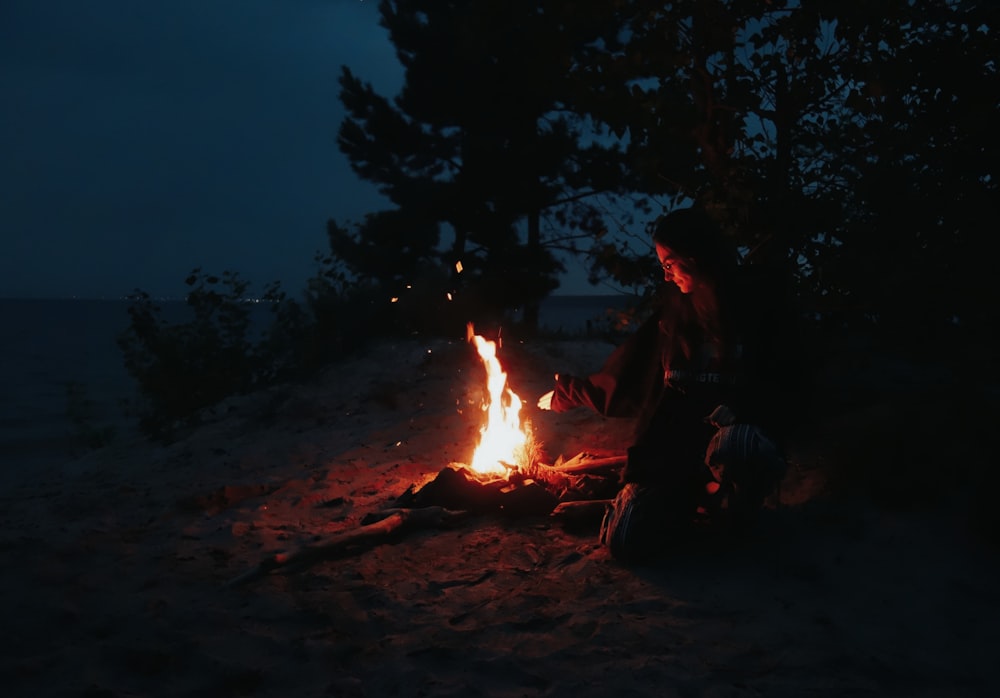 a person sitting in front of a campfire at night