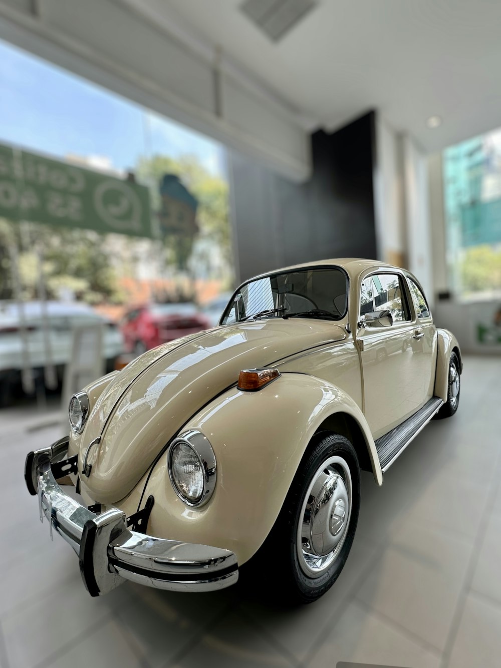 a beige vw bug is parked in a showroom