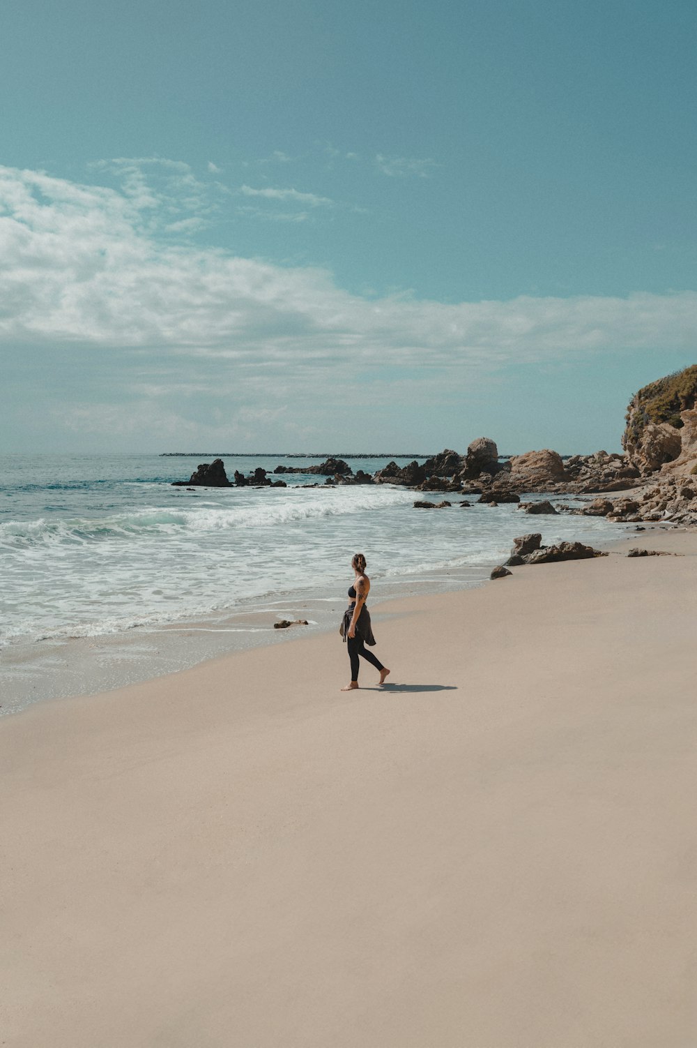 uma mulher caminhando ao longo de uma praia ao lado do oceano