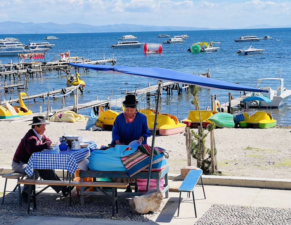 a couple of people sitting at a table under an umbrella