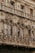 Ornate architectural facade featuring intricate details, including decorative columns, arches, and relief sculptures. The color is a weathered beige, giving an impression of age and historical significance.