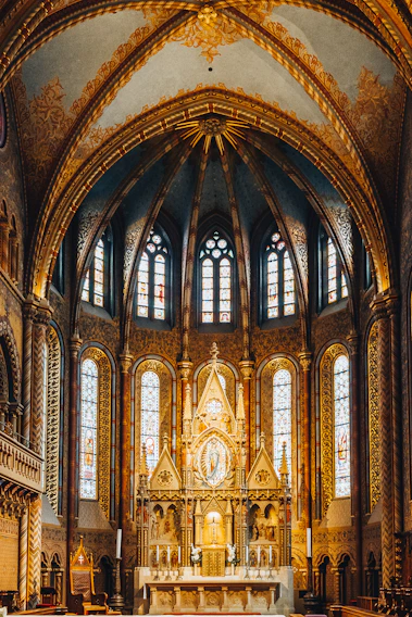 Majestic view of the church altar bathed in gold and burgundy light highlighting intricate details.