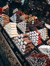 Assorted traditional Turkish delight pieces dusted with powdered sugar on a decorative plate.