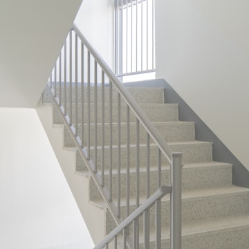 Elegant metal staircase with sleek stainless steel handrails illuminated by natural light.