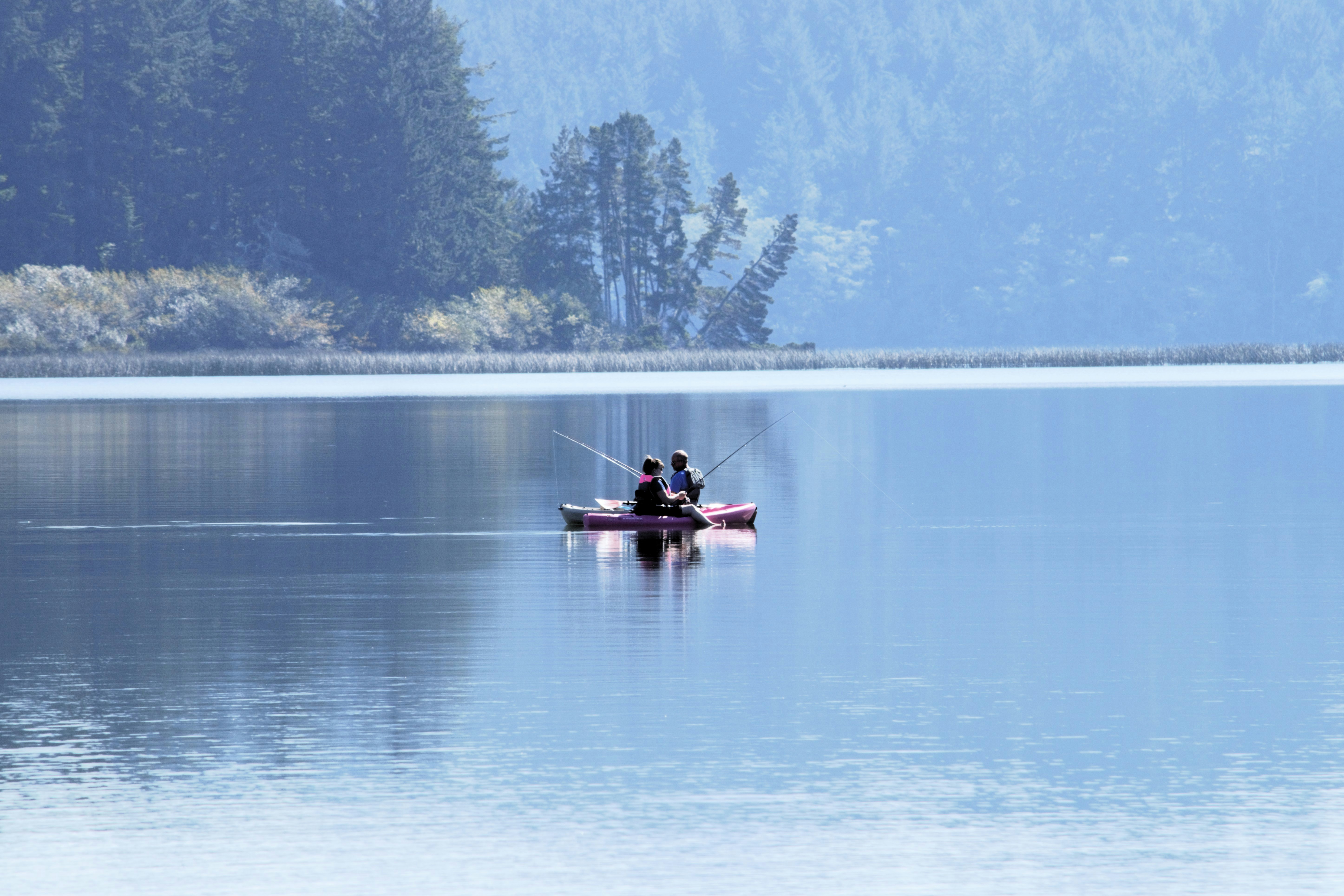 two people in a boat fishing on a lake