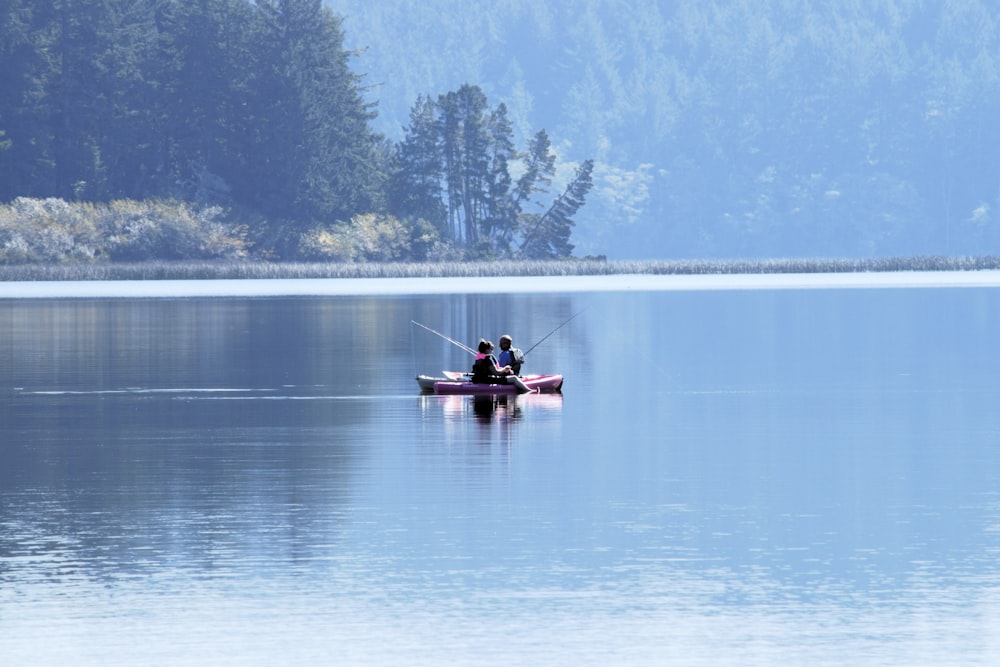 two people in a boat fishing on a lake