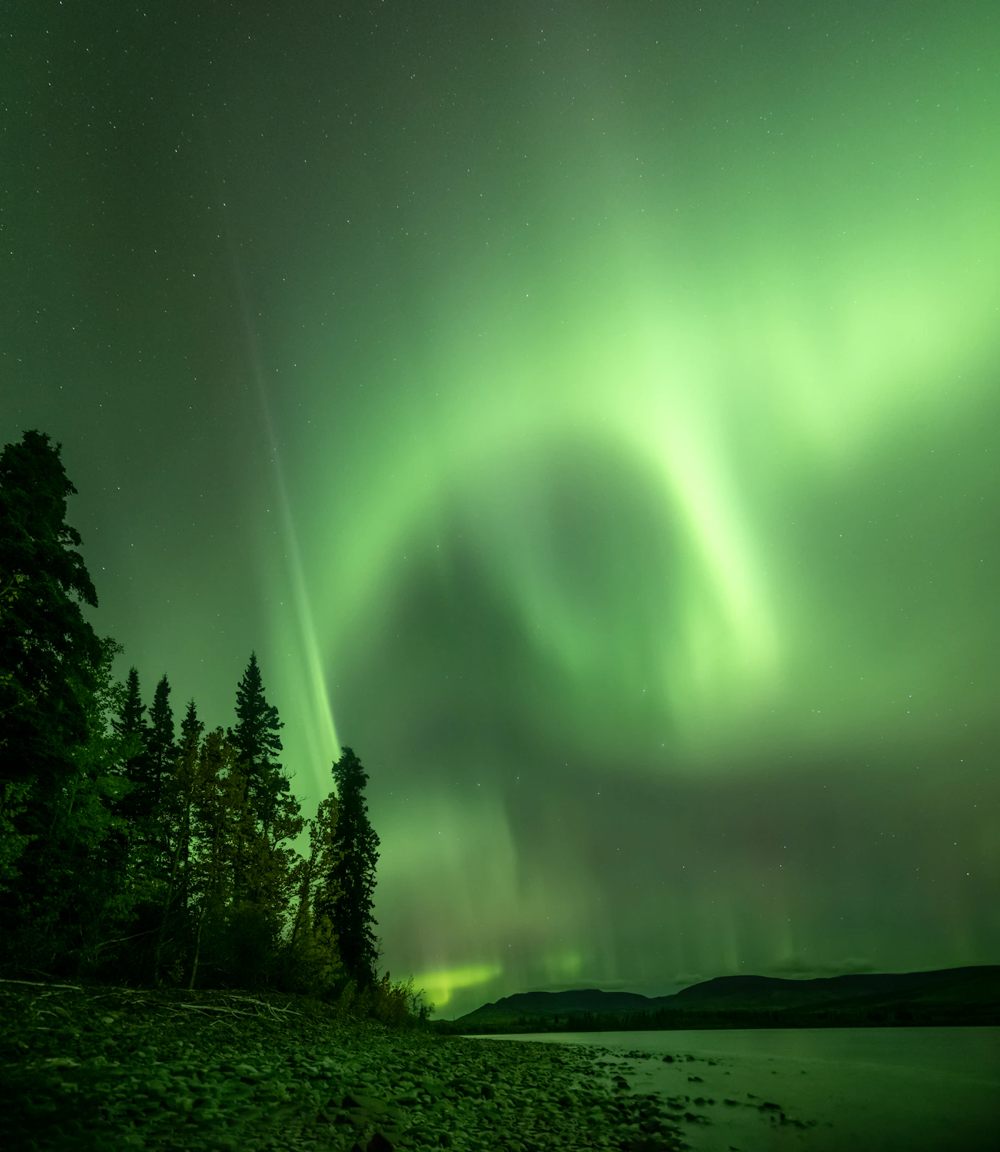 Aurora boréale verte au-dessus d'un plan d'eau — observation possible au Kamouraska pendant Solar Cycle 25