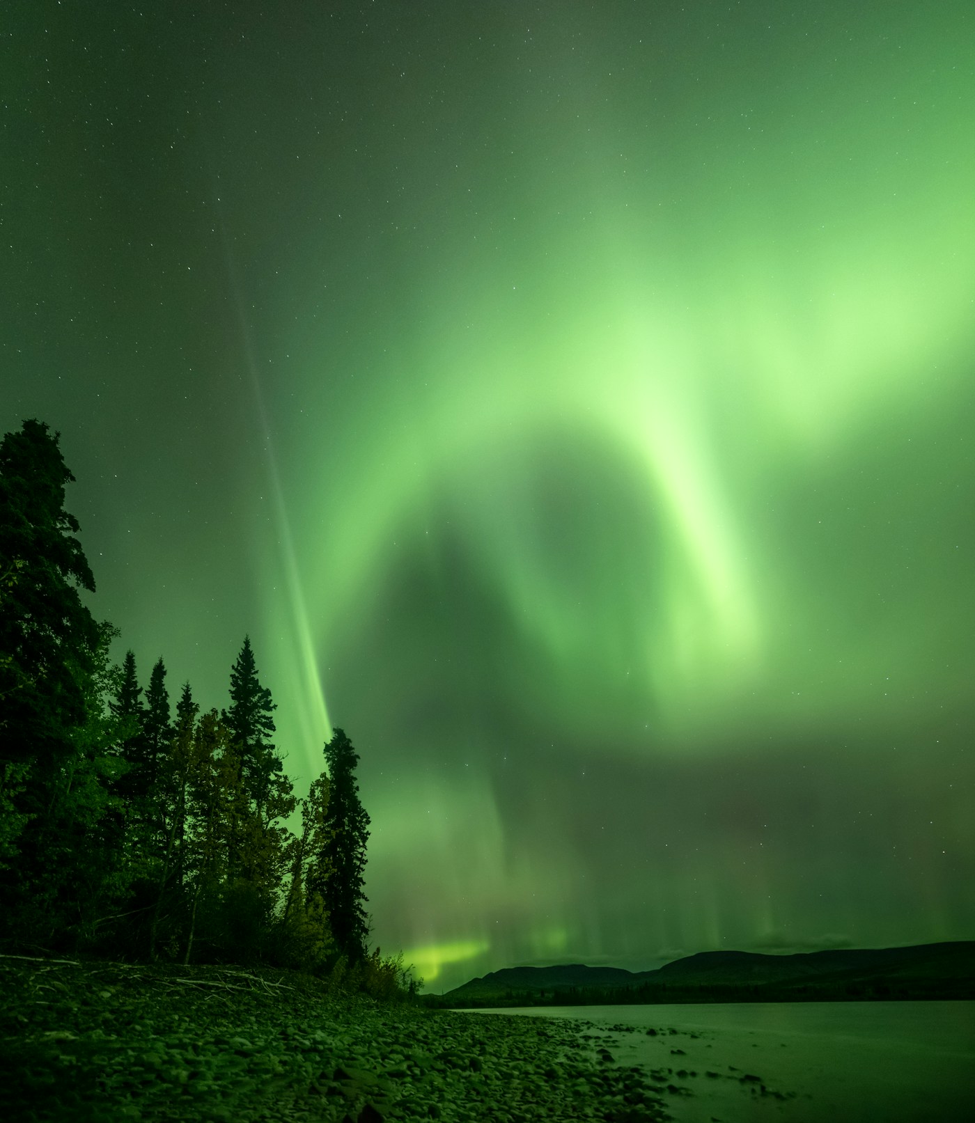 Aurora boréale verte au-dessus d'un plan d'eau — observation possible au Kamouraska pendant Solar Cycle 25