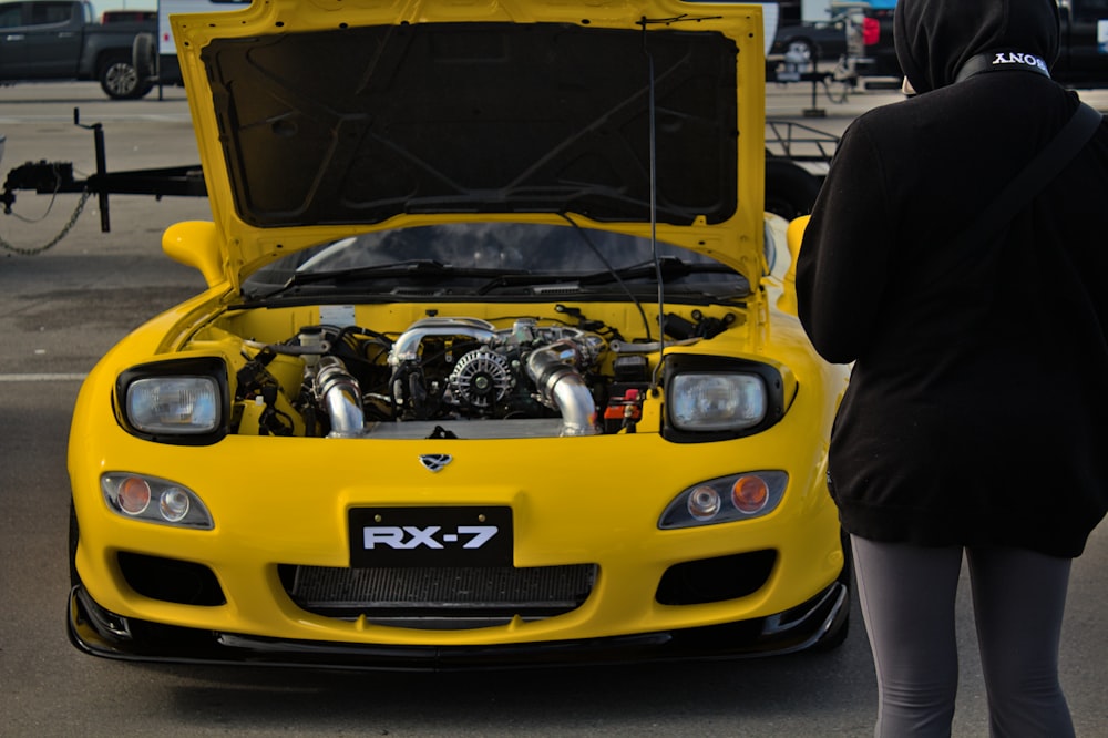 a woman standing next to a yellow sports car